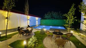 a group of people sitting around a table in a garden at night at Turon City Hotel in Samarkand