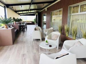 a lobby with white chairs and tables and a restaurant at Hotel Don Rodrigues in Tavira