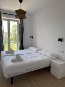 a bedroom with a large white bed with a window at Casuca Queveda in Santillana del Mar