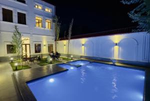 Una piscina frente a un edificio por la noche. en Turon City Hotel, en Samarkand