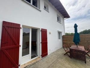 a patio with red doors and a bench and a house at Appartement cosy avec terrasse au calme in Urcuit