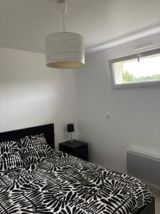 a bedroom with a black and white bed and a window at Appartement cosy avec terrasse au calme in Urcuit