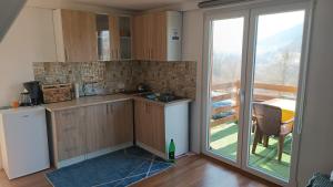 a kitchen with wooden cabinets and a sliding glass door at Sun-Moon Apartment in Zbilje