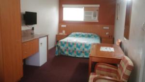 a room with a bedroom with a bed and a desk at Motel Monaco in Ipswich
