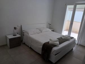 a white bedroom with a bed and a window at sosta modicana in Modica