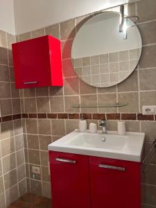 Un baño con un lavabo rojo y un espejo. en La Dolce Dimora, en Imola
