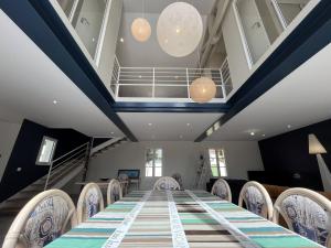 een lange tafel en stoelen in een kamer met trap bij La Villa l Olivier in La Flotte