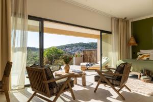 a bedroom with a bed and chairs and a balcony at Hôtel & Spa A Cala - Suites Piscines Privées - Adults Only in Conca +11 photos