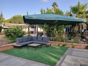 a patio with a blue couch and an umbrella at Spacious Garden Villa, private pool, huge grounds with orange trees in Dos Hermanas