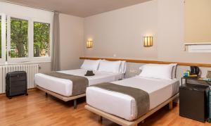 two beds in a room with two windows at Hotel Estel in Berga +25 photos