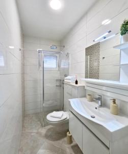 a white bathroom with a toilet and a sink at Apartments Andrijašević in Makarska