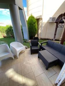 eine Terrasse mit einem blauen Sofa und weißen Stühlen in der Unterkunft Villa 4 bedrooms, Sedra resort, North coast in Sidi Kirayr