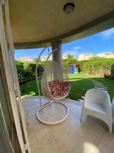 ein Korbstuhl auf einer abgeschirmten Veranda in der Unterkunft Villa 4 bedrooms, Sedra resort, North coast in Sidi Kirayr