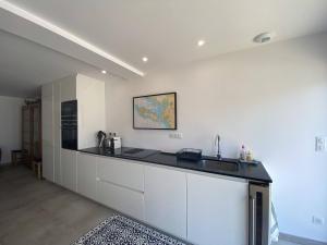 a kitchen with white cabinets and a black counter top at La Villa des Lauriers in La Flotte