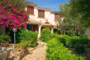 a house with a garden with pink flowers in front of it at Sa Capannizza in Limpiddu