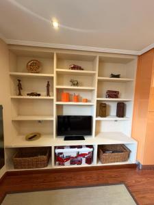 Una sala de estar con estantes blancos y un televisor. en Apartamento las Marismas Selnatur, en Llanes