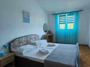 a bedroom with a bed and a blue window at Apartments Kočović in Peroj