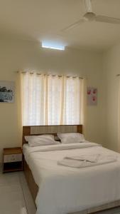 KaniyāmbettaにあるMIDDLE WAYANAD HOLYDAY Innの窓のある大きな白いベッドのある寝室