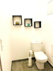 a bathroom with a toilet and three pictures on the wall at Appartement T2 Cosy in Villette-dʼAnthon