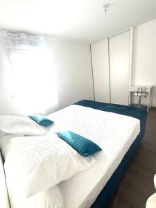 a bedroom with a white bed with blue pillows at Appartement T2 Cosy in Villette-dʼAnthon