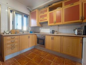 a kitchen with wooden cabinets and a tile floor at Oasis Vistamarina in El Médano