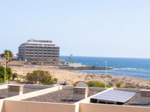 a view of a beach and a building with a table and chairs at Oasis Vistamarina in El Médano