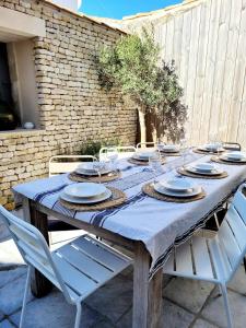 a wooden table with plates and glasses on it at La Maison du Puits Fleuri in Ars-en-Ré