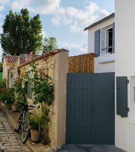 a green garage door in front of a house at La Maison du Puits Fleuri in Ars-en-Ré