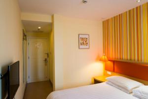 ハルビン市にあるHome Inn Harbin Sanda Dongli Road Haguoのベッドとテレビが備わるホテルルームです。