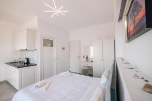 a white room with a bed and a kitchen at Mariana Apartments in Sarandë +174 photos