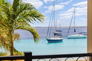 three boats in the water with a palm tree at Elegancia Ocean View with Cooling Pool in Kralendijk