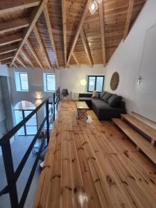 a living room with a black couch and a wooden floor at Beautiful Plomari Cottage in Plomarion