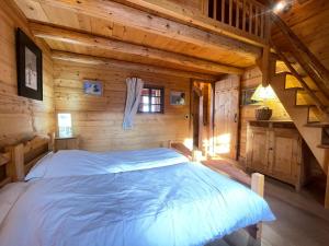 ein Schlafzimmer mit einem Bett in einer Holzhütte in der Unterkunft Chalet montagnard chaleureux avec poêle, terrasse et animaux acceptés - FR-1-505-154 in Notre-Dame-de-Bellecombe