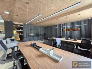 una sala conferenze con un grande tavolo e sedie in legno di Get by Side Suites a Tambaú