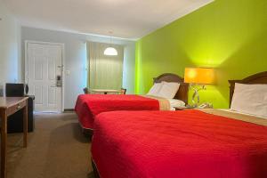 a hotel room with two beds and green walls at OYO Hickory House Inn in Dexter
