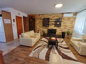 a living room with white furniture and a brick wall at Ágica Vendégház in Andornaktálya