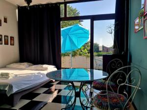 a room with a table and a bed and a blue umbrella at Apartmani Jessica in Novalja