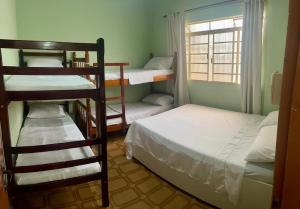 ein Zimmer mit drei Etagenbetten und einem Fenster in der Unterkunft Pousada Nossa Senhora de Laus in Cachoeira Paulista