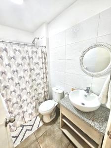 een badkamer met een toilet, een wastafel en een spiegel bij Dpto acogedor con terraza privada in Lima