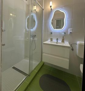 a bathroom with a shower and a sink and a mirror at Livada Studio Apartments in Braşov