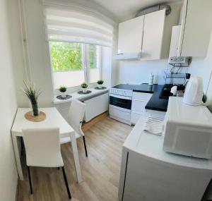 a kitchen with white cabinets and a table and chairs at Stylish apartment in Central City, near D-Terminal in Tallinn