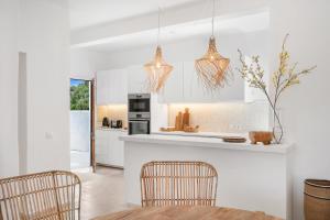 una cucina con mobili bianchi, tavolo e sedie di Villa Bini Ezolea a Binibeca