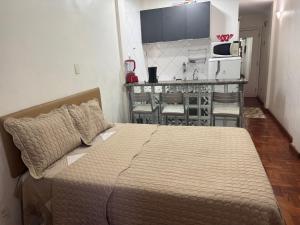 a bedroom with a large bed and a kitchen at STUDIO IPANEMA CONFORTÁVEL in Rio de Janeiro
