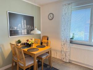 a dining room table with chairs and a clock on the wall at Apartment in South West Stockholm w Balcony near Metro, convenient to Avicii Arena, 3 Arena, Friends Arena and Royal Opera in Stockholm