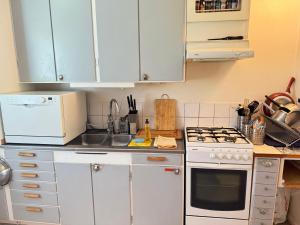 a kitchen with white cabinets and a white stove top oven at Apartment in South West Stockholm w Balcony near Metro, convenient to Avicii Arena, 3 Arena, Friends Arena and Royal Opera in Stockholm +14 photos