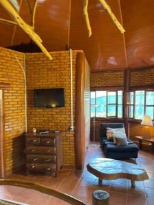 - un salon avec un canapé et une télévision sur un mur en briques dans l'établissement Pousada Fazenda São Bento, à Alto Paraíso de Goiás 82 autres photos