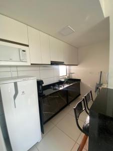a kitchen with white cabinets and a black refrigerator at Flat em Caruaru in Caruaru