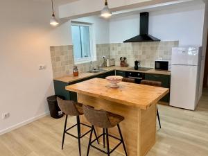 a kitchen with a wooden island with chairs and a refrigerator at Apartamentos do porto Malpica in Malpica