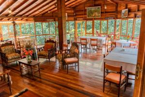 ein Restaurant mit Tischen und Stühlen in einem Raum mit Fenstern in der Unterkunft Cabañas Germany in Puyo