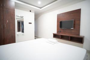 Royal Majestic Lodge في غاواهاتي: غرفة نوم بها سرير وتلفزيون على الحائط